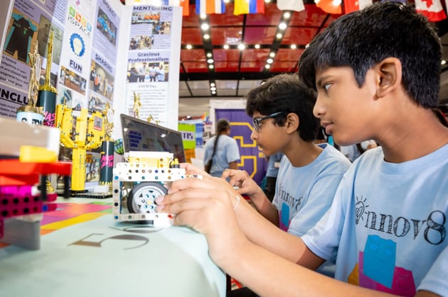 FIRST students focused on a computer and robot at a FIRST event. 