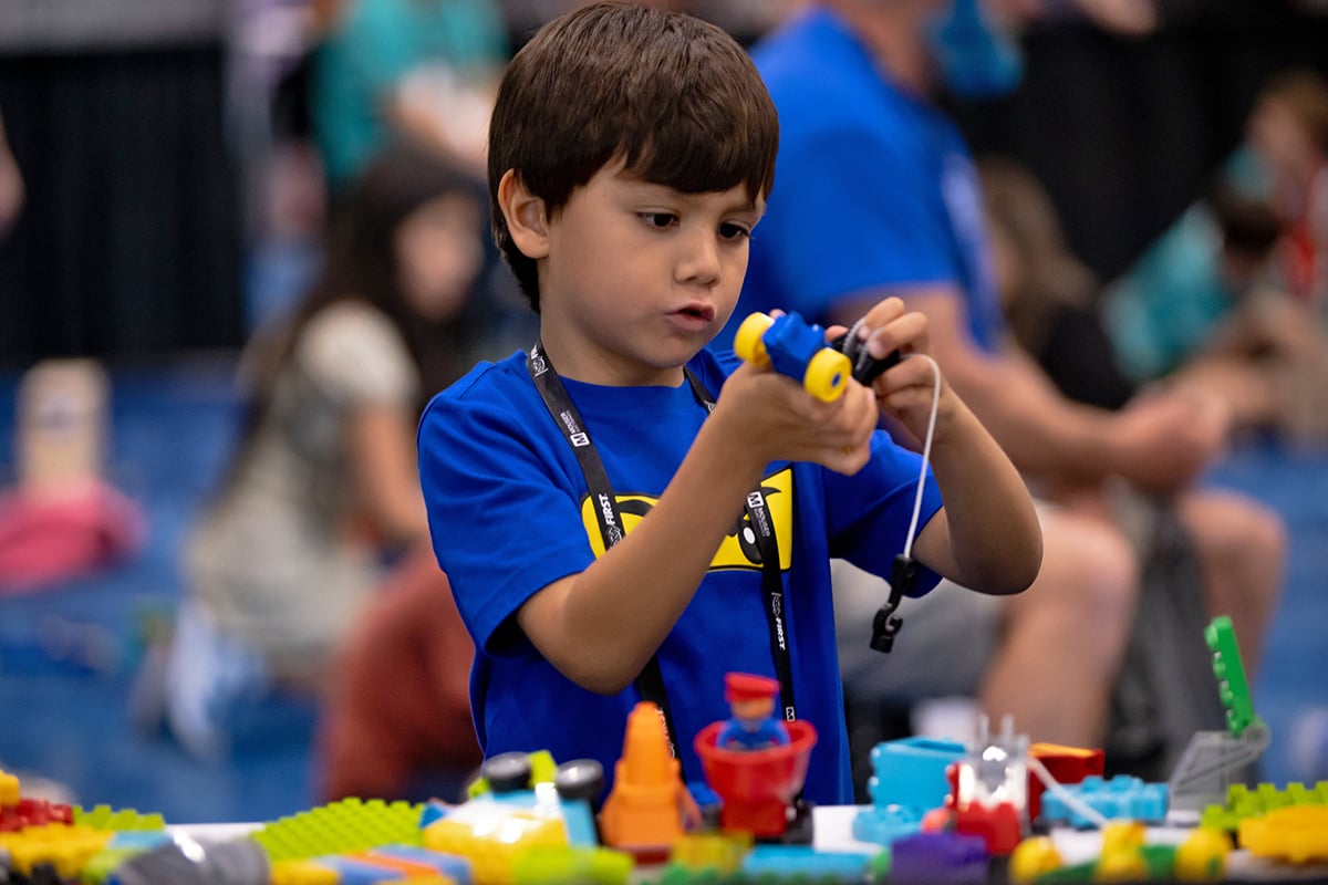 A young child is building with LEGO bricks at FIRST Championship.