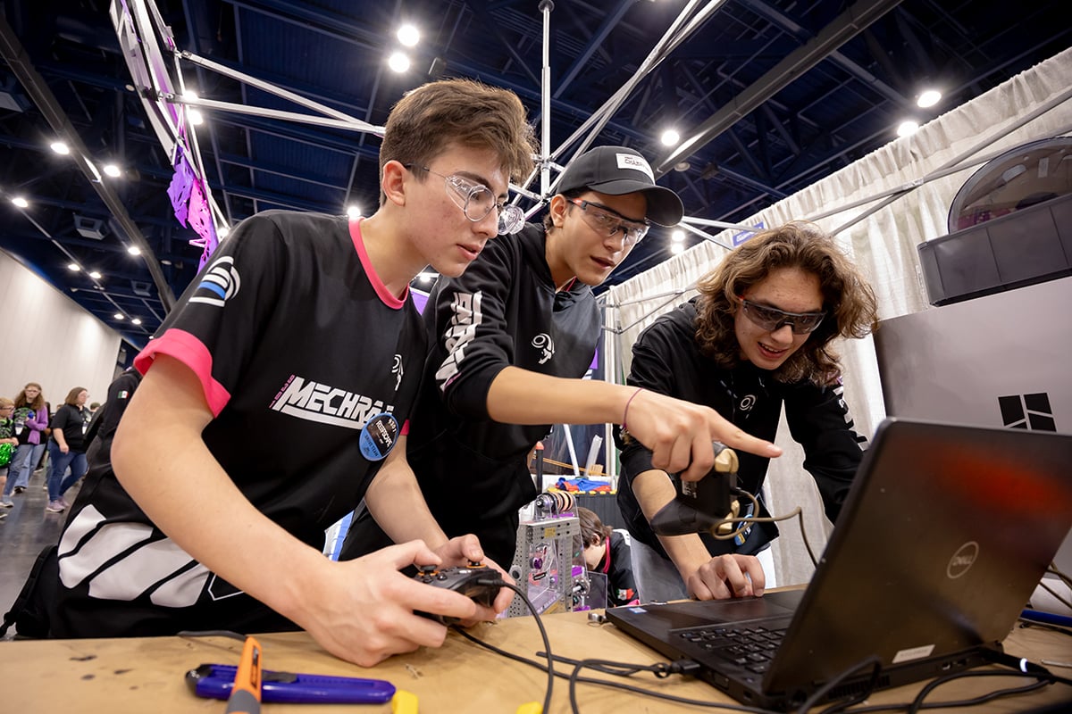 Three FIRST Robotics Competition students programming robot at FIRST Championship.